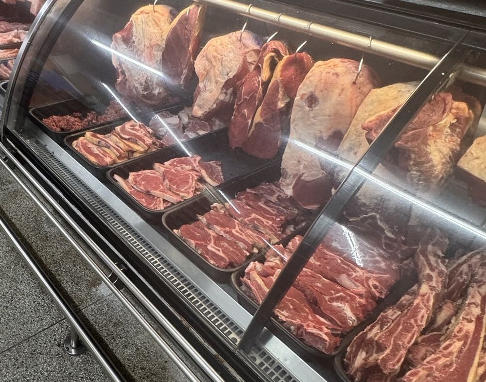 Balcão refrigerado de açougue de supermercado com cortes bovinos e suínos expostos